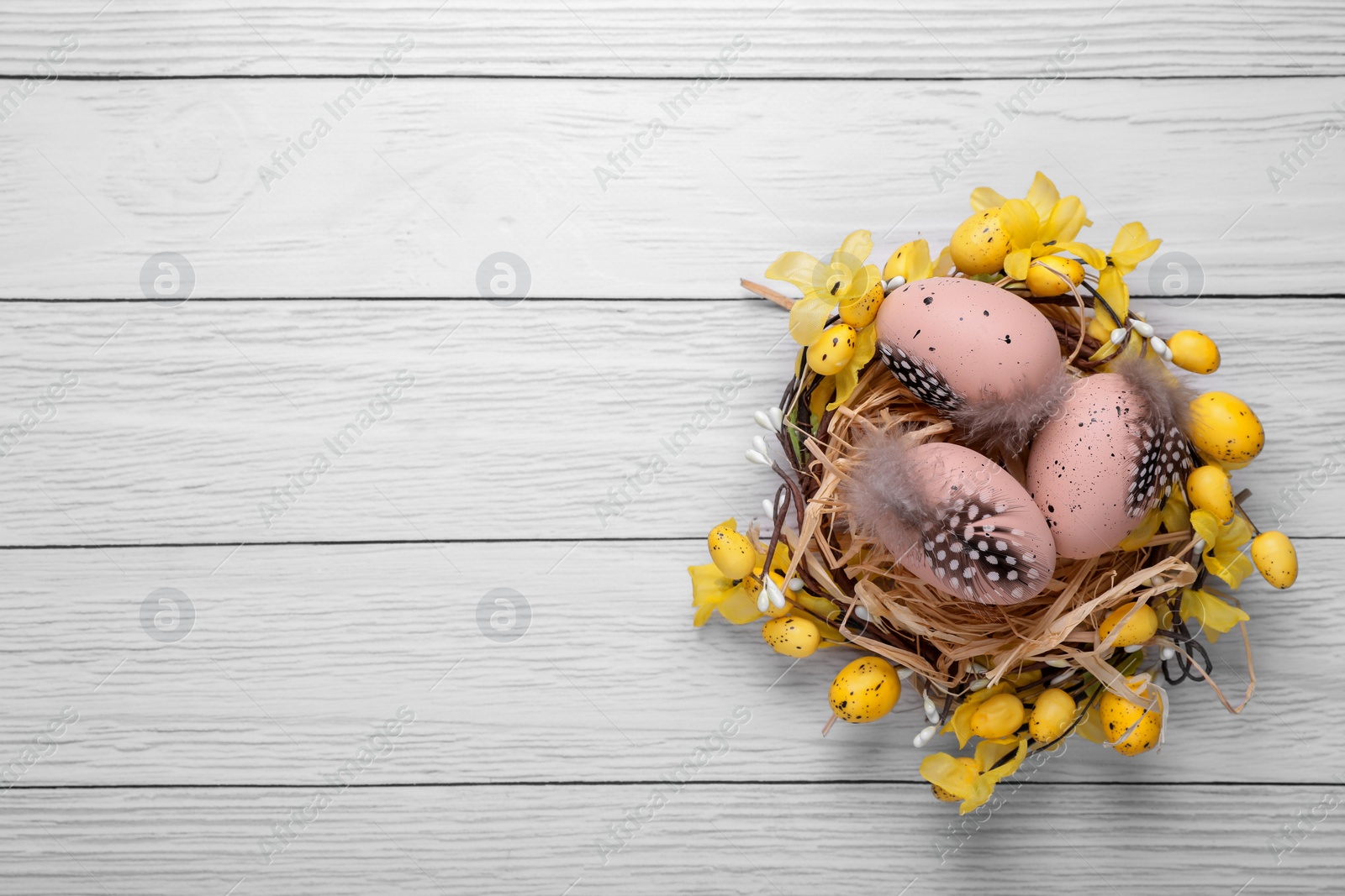 Photo of Festively decorated Easter eggs on white wooden table, top view. Space for text