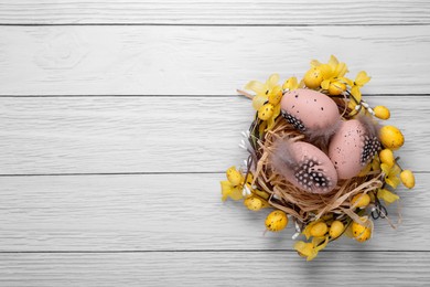 Photo of Festively decorated Easter eggs on white wooden table, top view. Space for text
