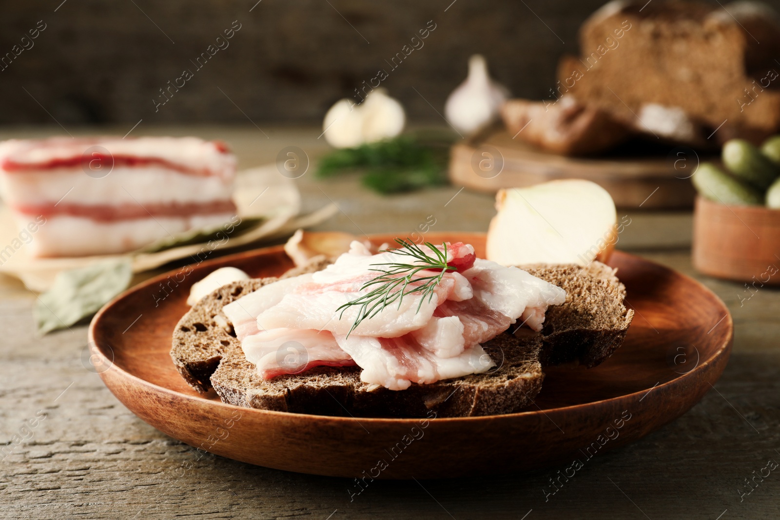 Photo of Tasty salt pork with rye bread and dill on wooden table