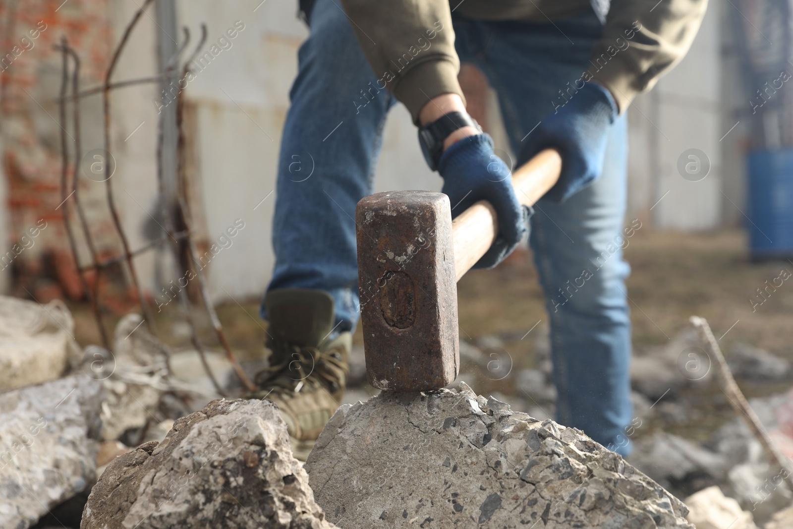 Photo of Man breaking stones with sledgehammer outdoors, closeup