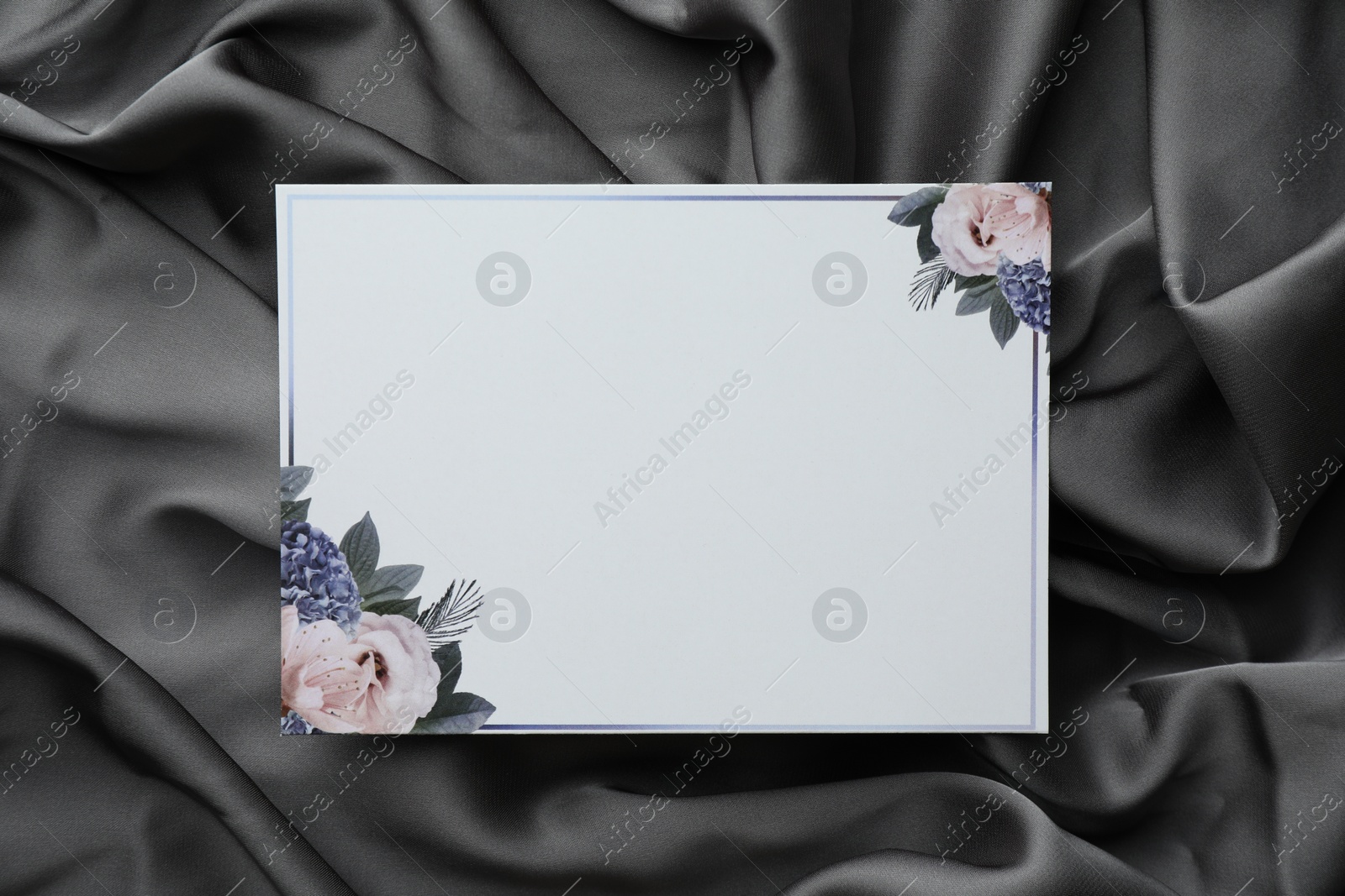 Photo of Blank invitation card on black fabric, top view