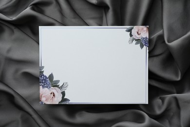 Blank invitation card on black fabric, top view