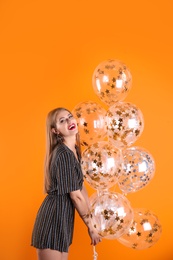 Young woman with air balloons on color background