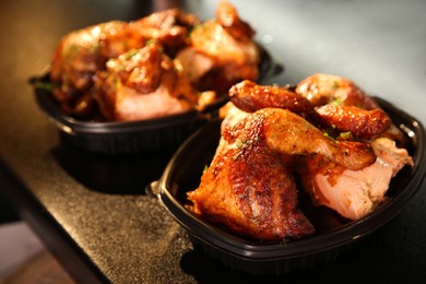 Cooked pieces of grilled chicken in plastic containers on bar counter. Food delivery service