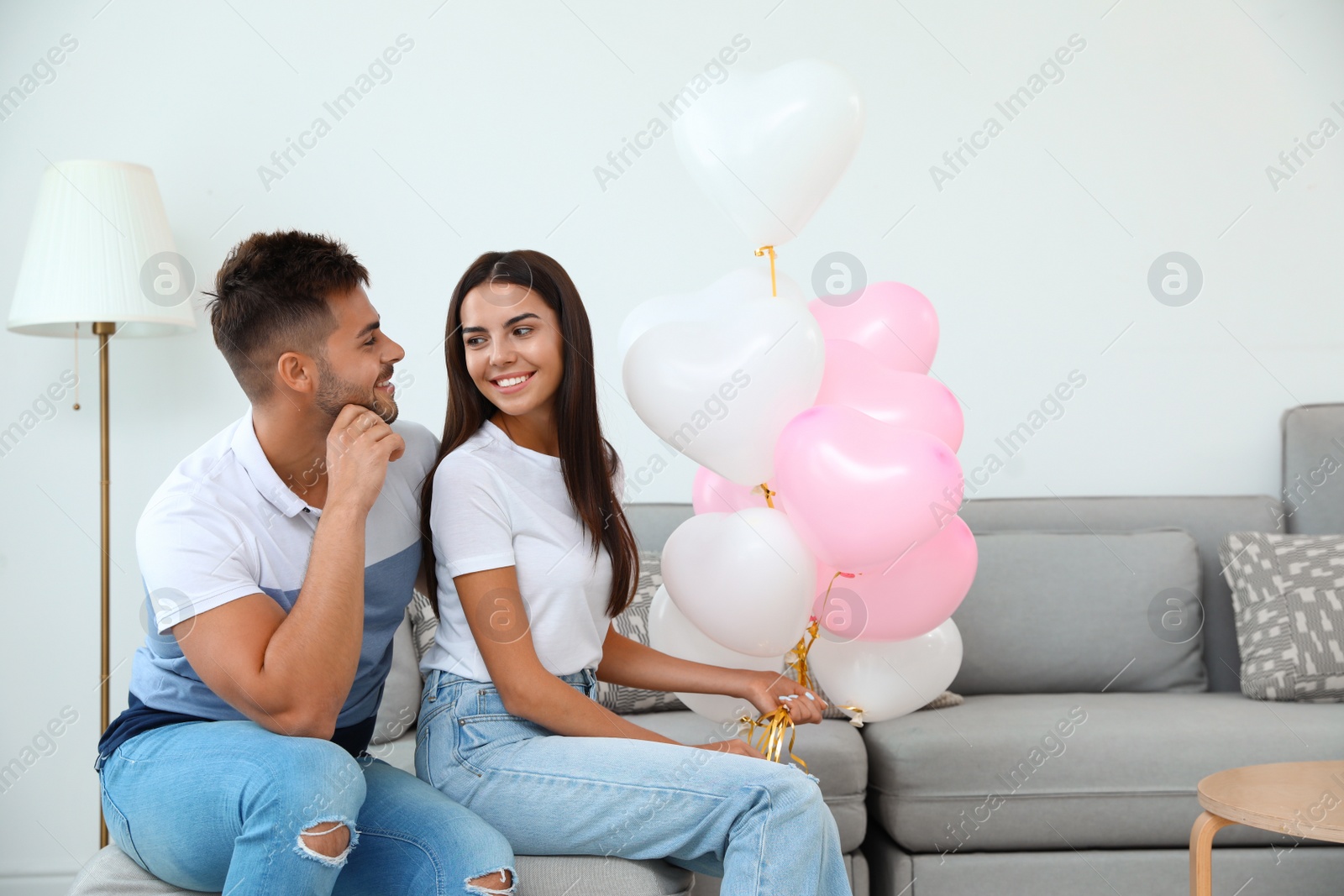 Photo of Young couple with air balloons at home. Celebration of Saint Valentine's Day