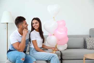 Young couple with air balloons at home. Celebration of Saint Valentine's Day