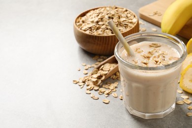 Photo of Glass of tasty banana smoothie with oatmeal on light grey table. Space for text