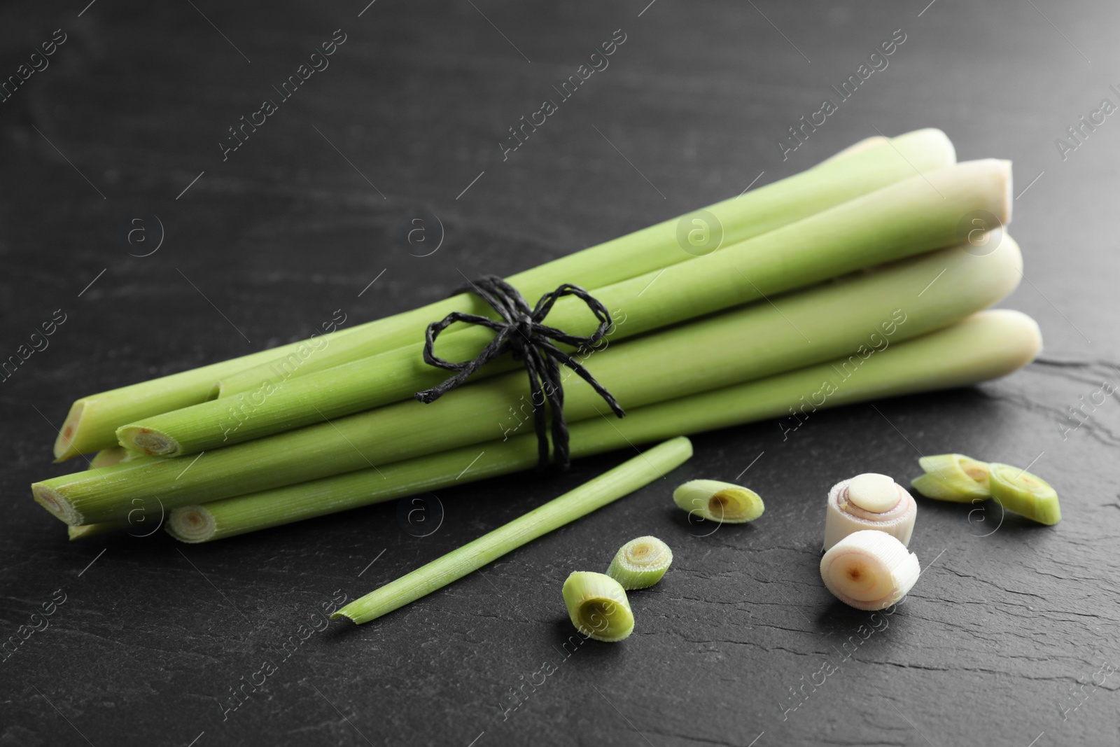 Photo of Bunch of fresh lemongrass stalks on black table