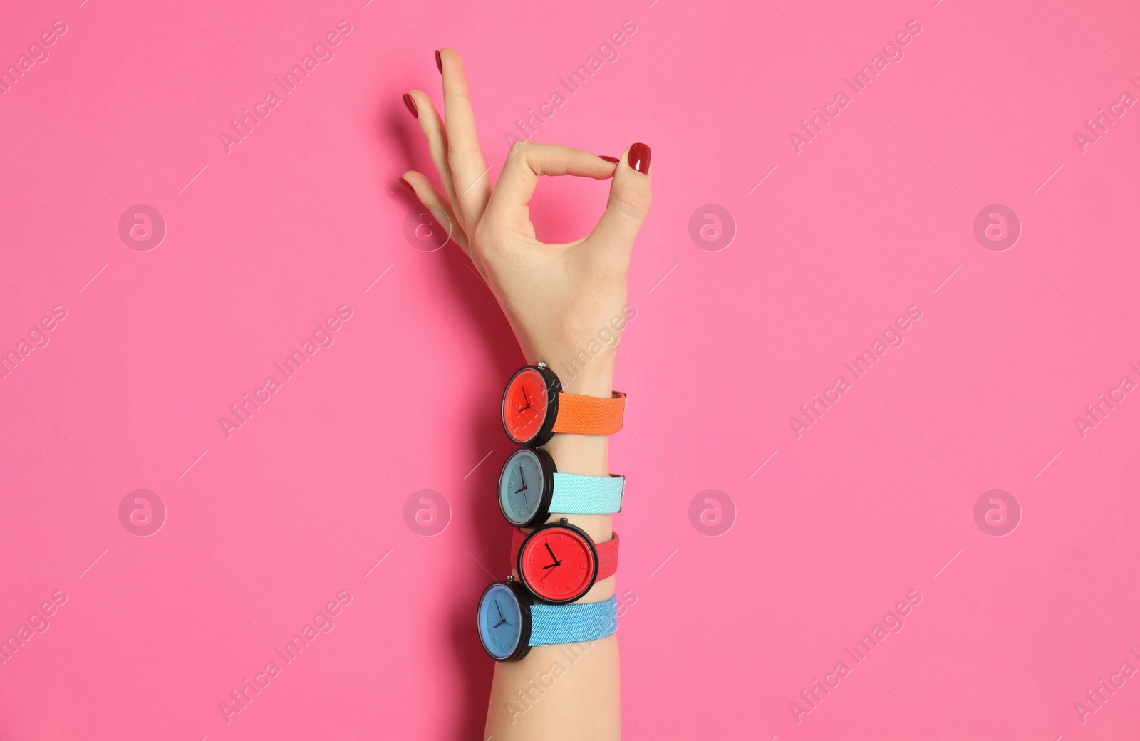 Photo of Woman with many bright wrist watches on color background, closeup. Fashion accessory