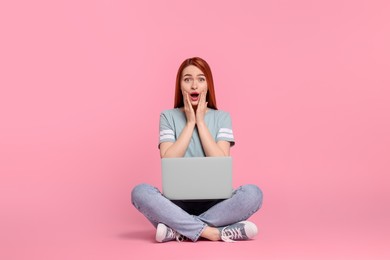 Surprised young woman with laptop on pink background