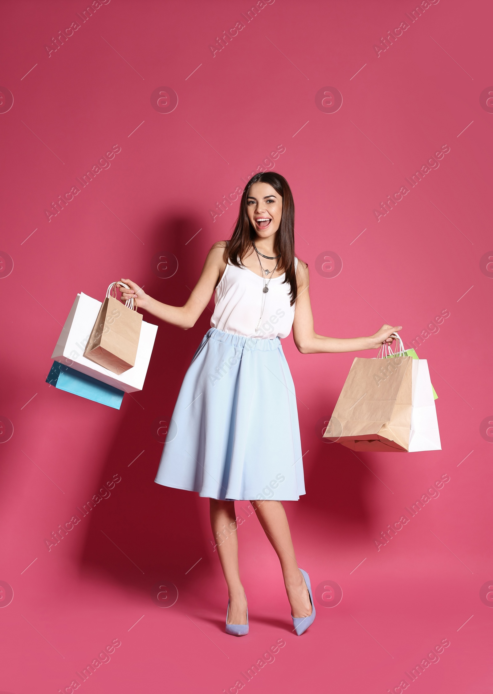 Photo of Young woman with shopping bags on color background