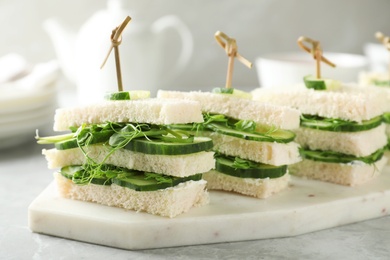 Photo of Board with traditional English cucumber sandwiches on table