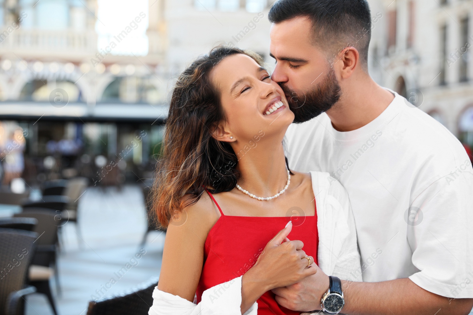 Photo of Handsome young man kissing his beautiful girlfriend on city street