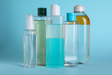 Photo of Bottles of micellar water on light blue background
