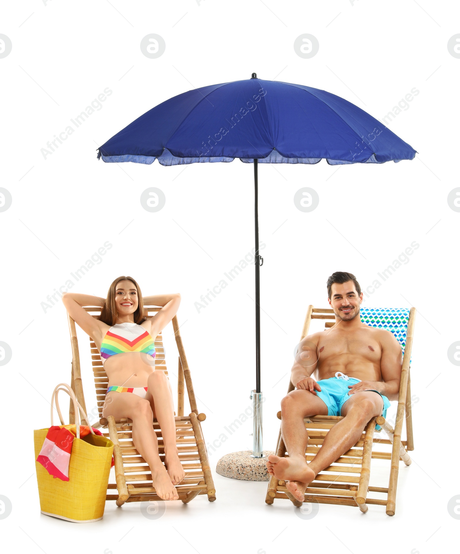 Photo of Young couple with beach accessories on sun loungers against white background