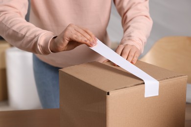 Seller taping parcel at workplace, closeup view