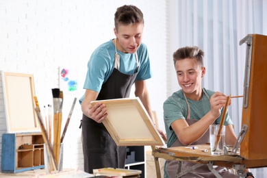 Photo of Teenage twin brothers having painting class in workshop. Hobby club