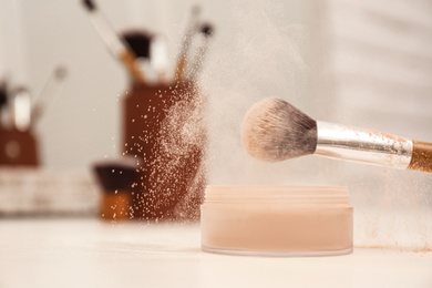 Photo of Professional brush of makeup artist and powder on dressing table