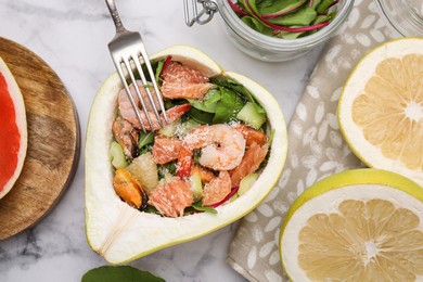 Photo of Delicious pomelo salad with shrimps in half of fruit on white marble table, flat lay