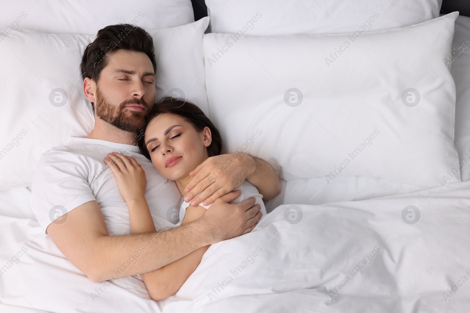 Photo of Lovely couple sleeping together in bed at home, top view. Space for text