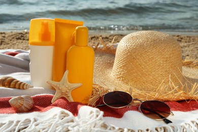 Sun protection products and beach accessories on blanket near sea