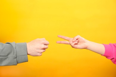 Photo of People playing rock, paper and scissors on orange background, closeup
