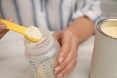 Photo of Woman preparing infant formula at table, closeup. Baby milk