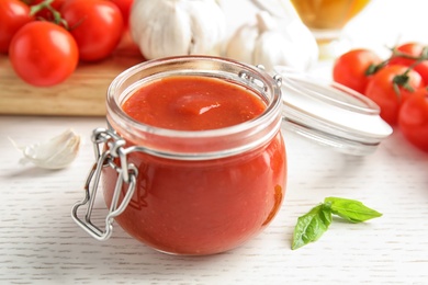 Photo of Jar of tasty tomato sauce on wooden table, closeup