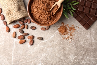 Flat lay composition with cocoa powder, beans and chocolate on light background