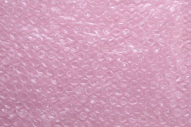 Transparent bubble wrap on pink background, top view