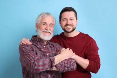 Happy son and his dad on light blue background