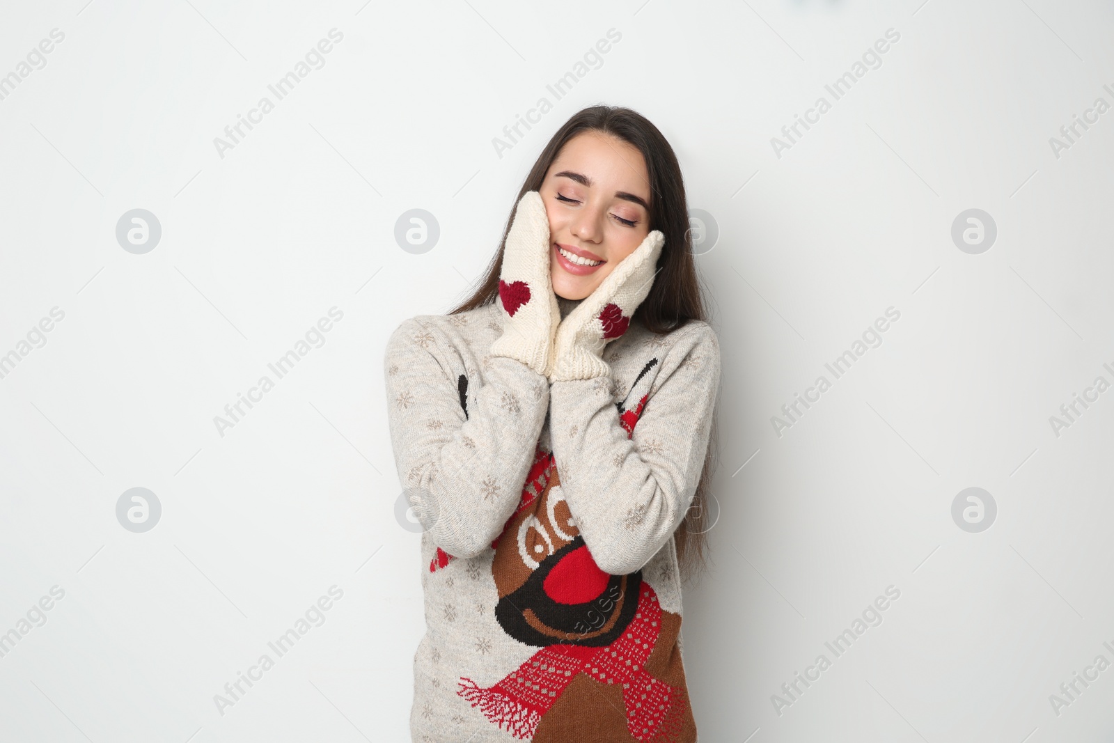 Photo of Young woman in Christmas sweater and mittens on white background