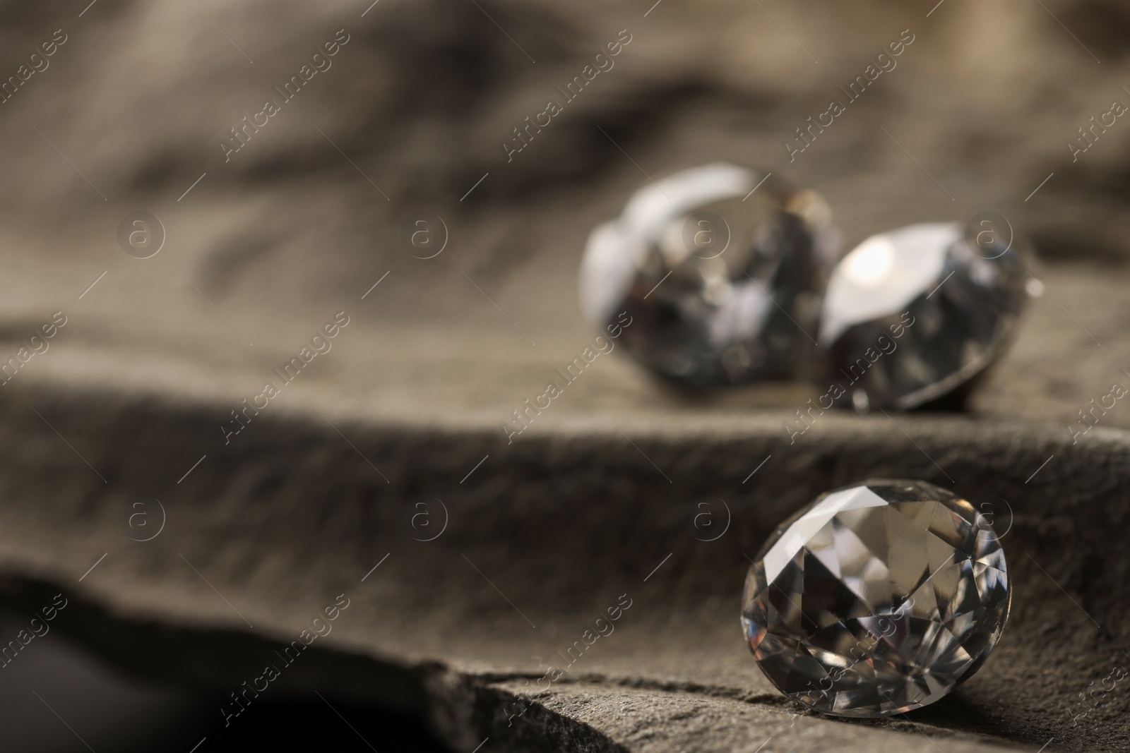 Photo of Three beautiful gemstones for jewelry on stone surface, closeup. Space for text