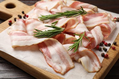 Slices of raw bacon and spices on wooden table, closeup