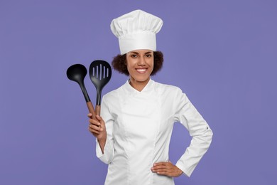 Photo of Happy female chef in uniform holding skimmer and ladle on purple background