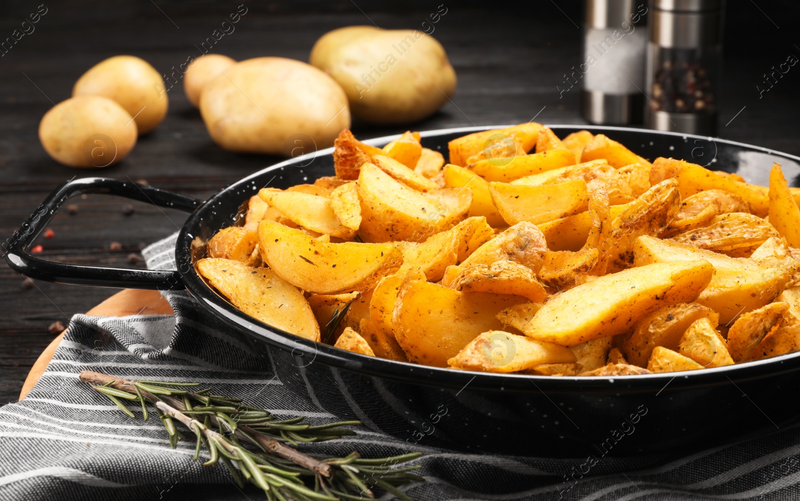 Photo of Dish of delicious oven baked potatoes on table, closeup