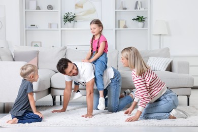 Photo of Happy family having fun together on soft rug at home
