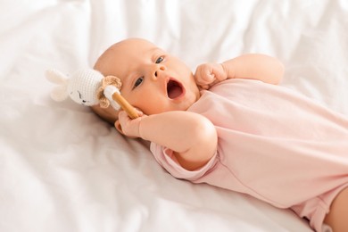 Photo of Cute little baby with toy on white sheets