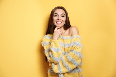 Beautiful young woman in warm sweater on color background