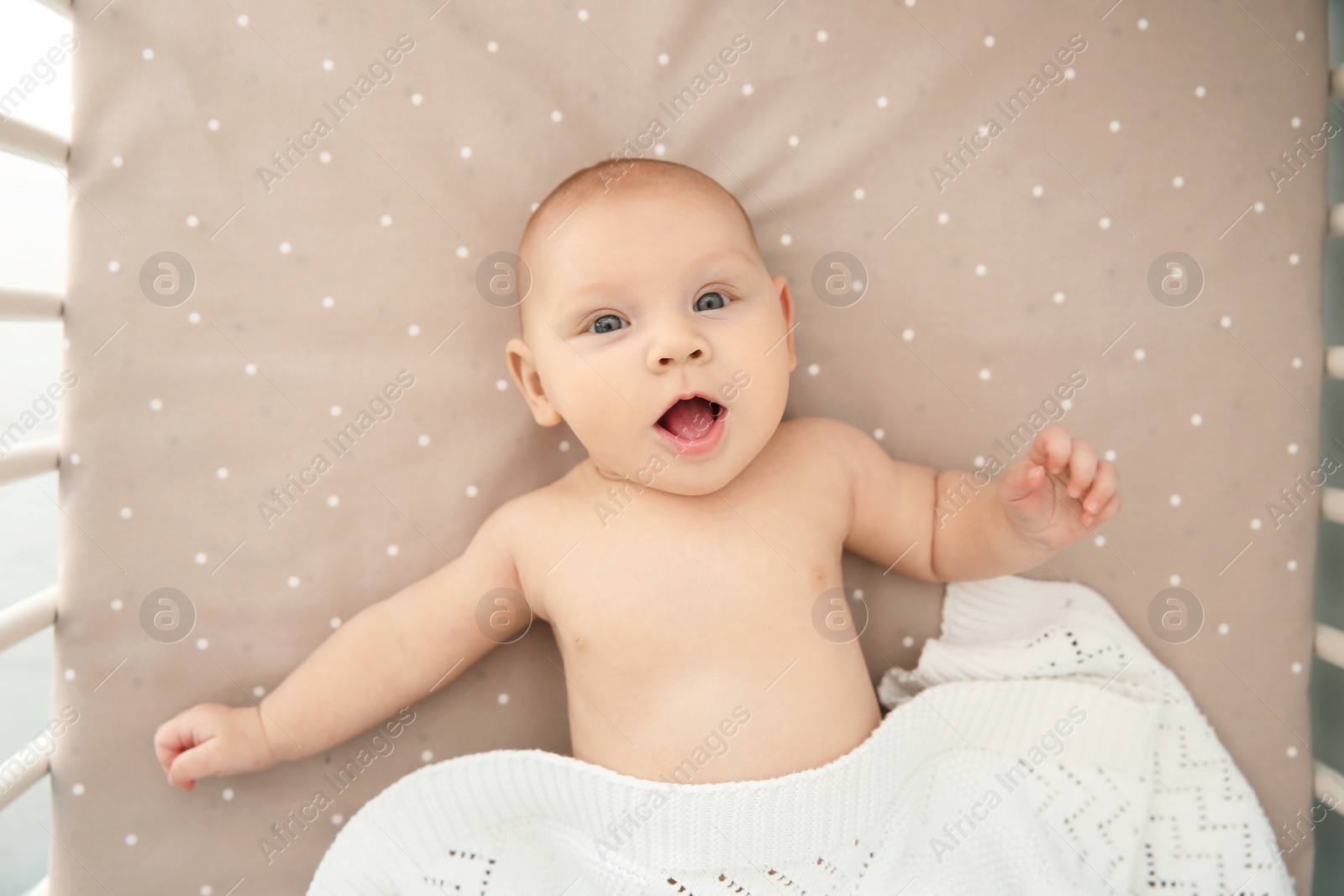 Photo of Adorable baby girl lying in bed, top view