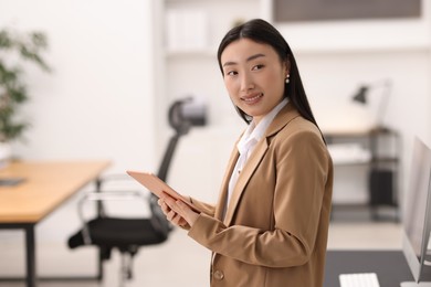 Portrait of smiling businesswoman with tablet in office. Space for text