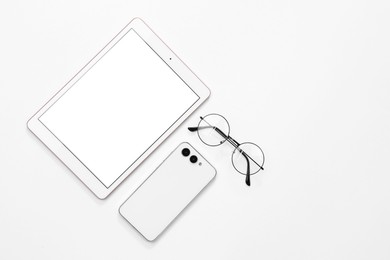Photo of Modern tablet, smartphone and glasses on white background, flat lay. Space for text