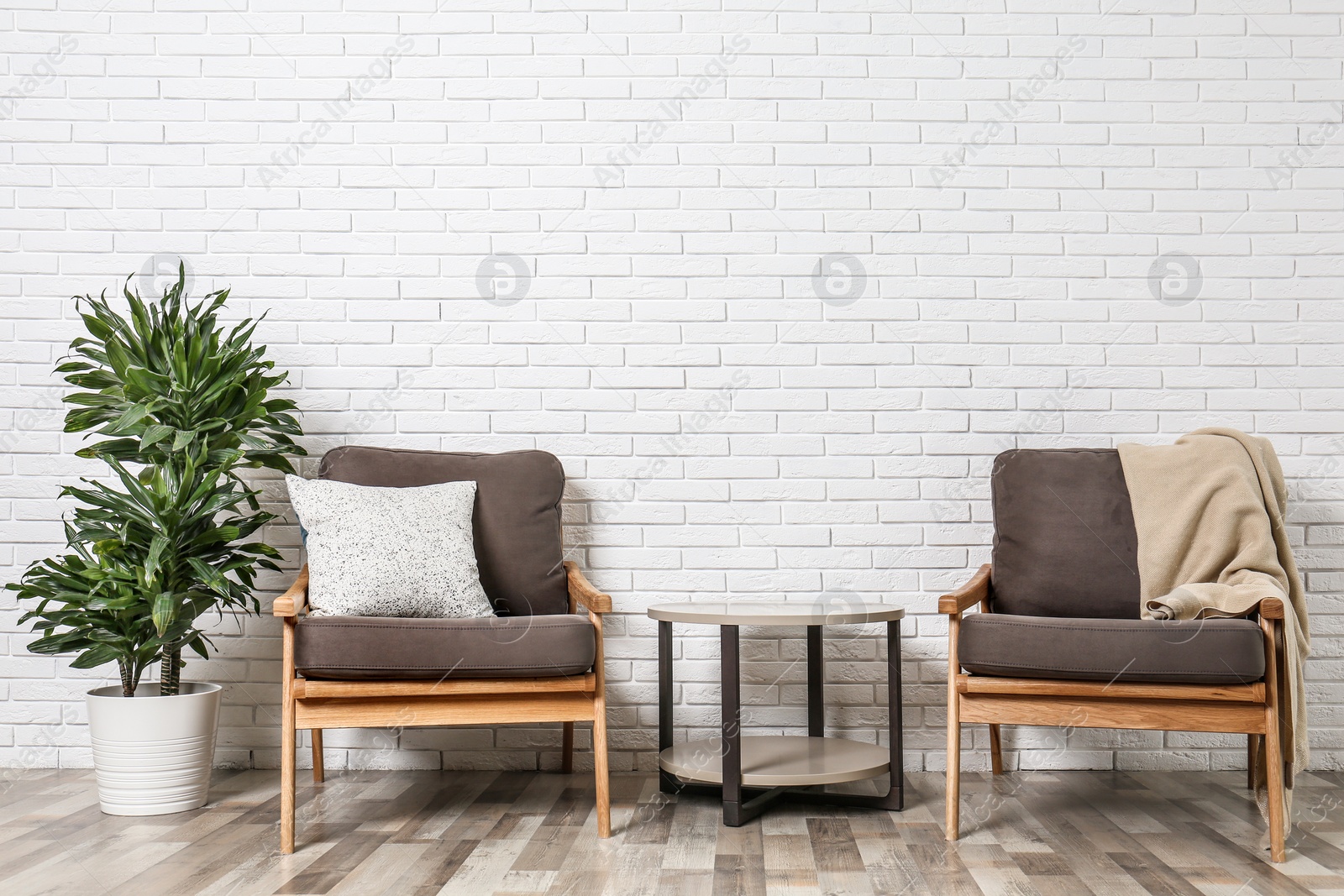 Photo of Room interior with modern armchairs and table near white brick wall