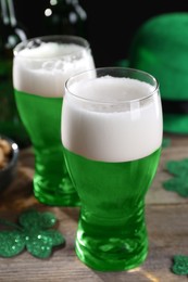 Photo of St. Patrick's day party. Green beer and decorative clover leaves on wooden table, closeup