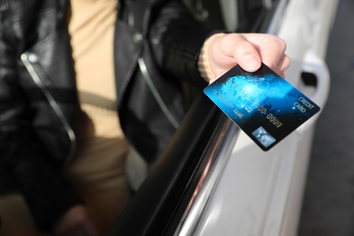 Photo of Woman sitting in car and giving credit card at gas station, closeup