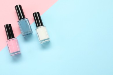 Bright nail polishes in bottles on color background, flat lay. Space for text