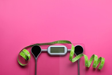 Photo of Electronic scales and measuring tape on pink background, flat lay. Space for text