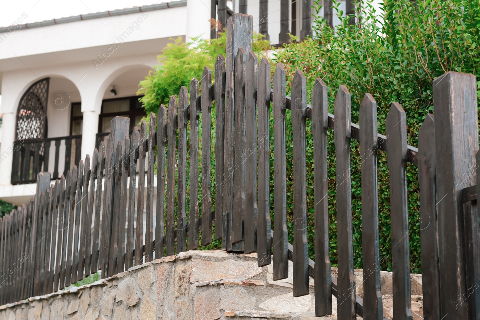 Photo of Low wooden shabby fence near building outdoors