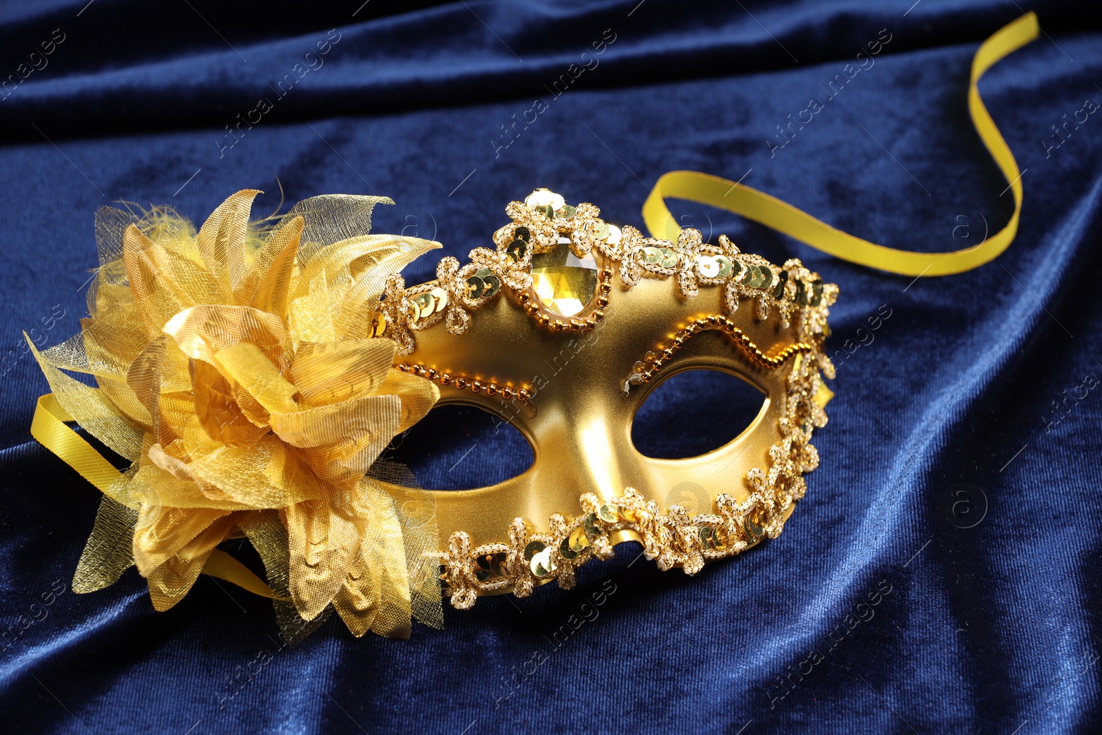 Photo of Theater arts. Golden venetian carnival mask on blue fabric, closeup