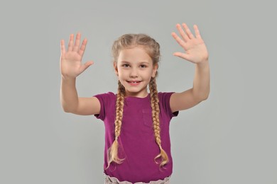 Photo of Happy girl giving high five with both hands on light grey background